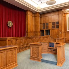Old Style Courtroom with brown desks and a red backdrop