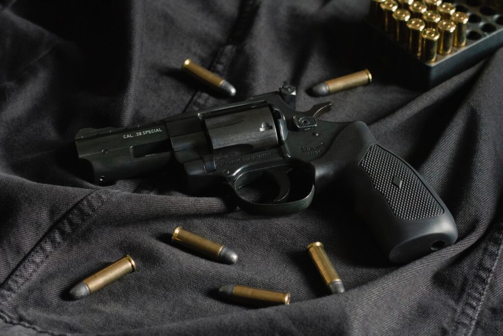 Dark colored handgun revolver with cartridge casings surrounding it