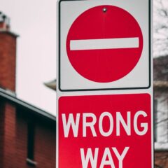 Wrong Way Sign with symbol for wrong way on top and letters wrong way on bottom. Colors are red and white.
